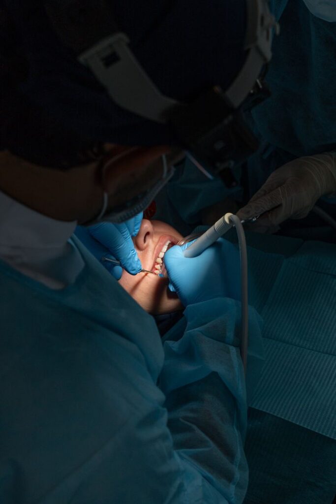 A dentist and assistant using dental instruments during a procedure in a clinic.