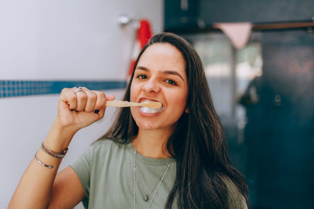Portrait of a young woman brushing her teeth indoors, promoting dental hygiene.